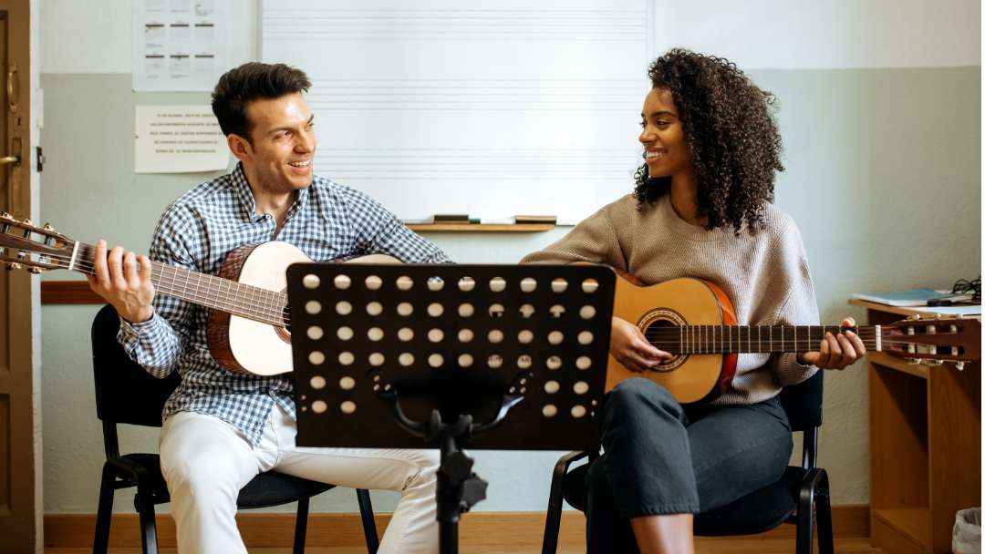 Adult Male and Female learning how to play a guitar.
