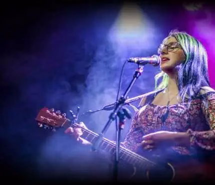 bkgnd_rpma_wtpiab-2 A woman performing a song on stage